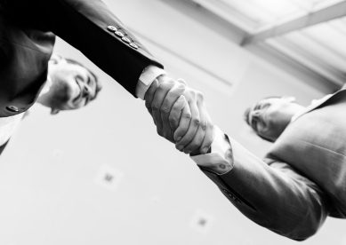 image looking up at two business men shaking hands